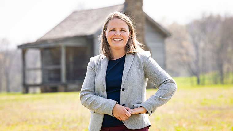Dr. Philippa Koch poses in front of a farmhouse.