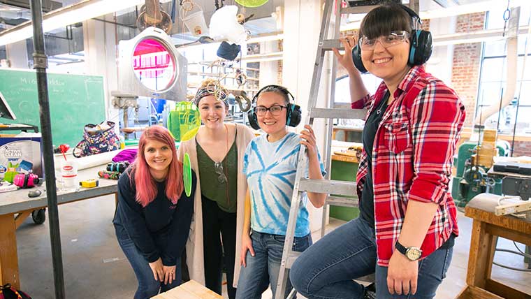 Four smiling Missouri State students within a classroom